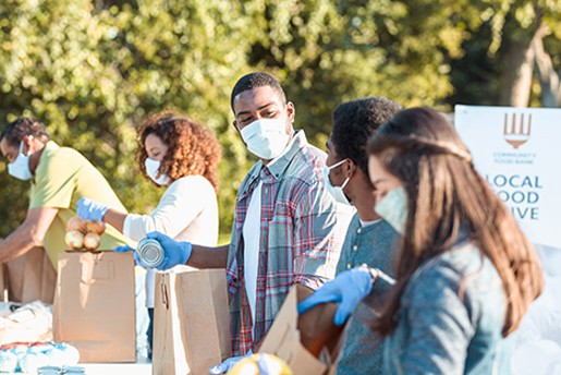 Recent graduates volunteering at an outdoor food drive. 